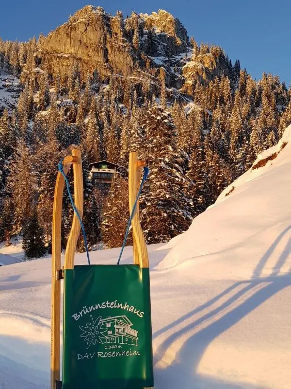 Rodel vor dem Brünnsteinhaus und Brünnstein | © Yvonne Tremml